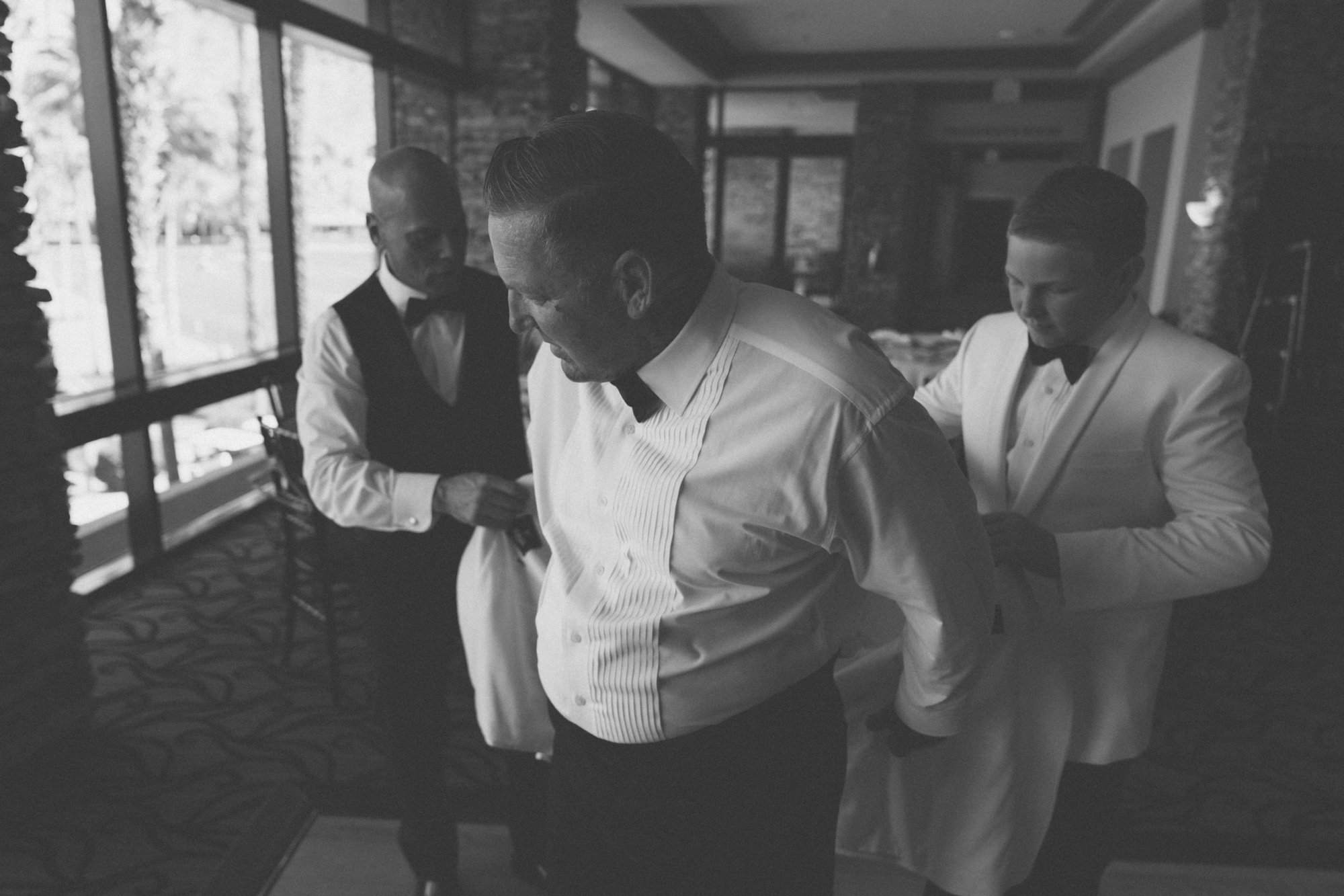 Groom getting ready with groomsmen — Coachella Valley wedding photography in black and white