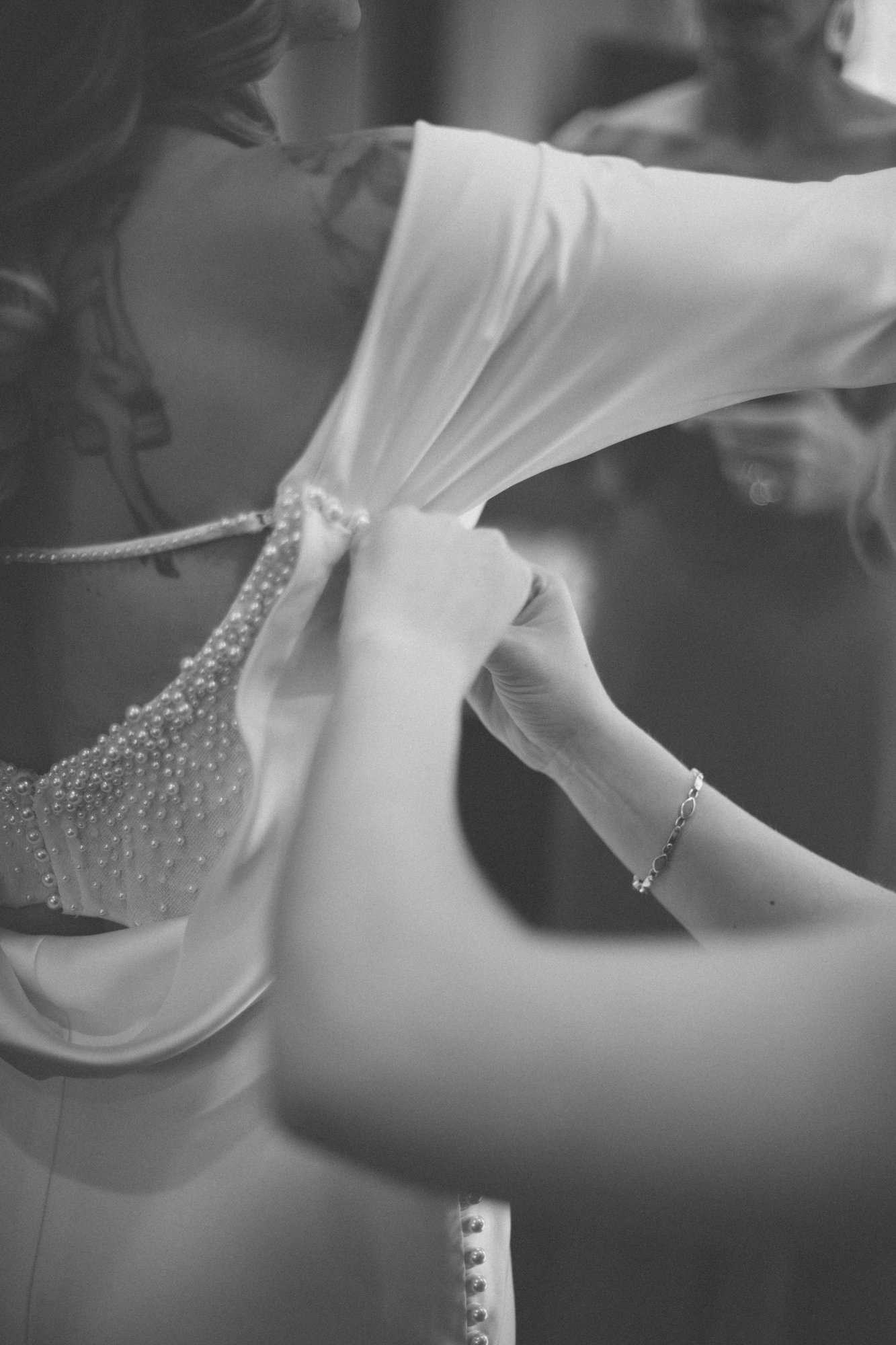 Bride getting ready — lacing the back of the dress, intimate detail captured by Manuel & Alma